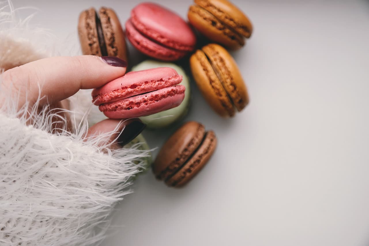 Pink nails picking up a macaron
