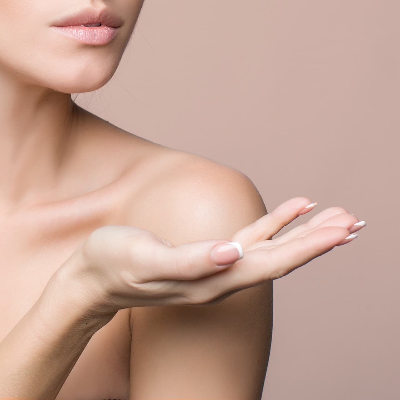 A hand with soft, natural-looking pale nails against a blush background